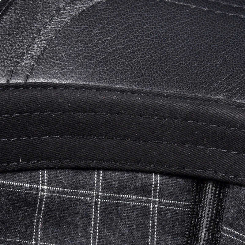 Black leather cap brim edge close-up with stitched band and plaid lining
