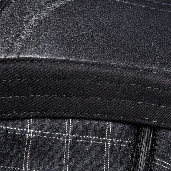 Black leather cap brim edge close-up with stitched band and plaid lining