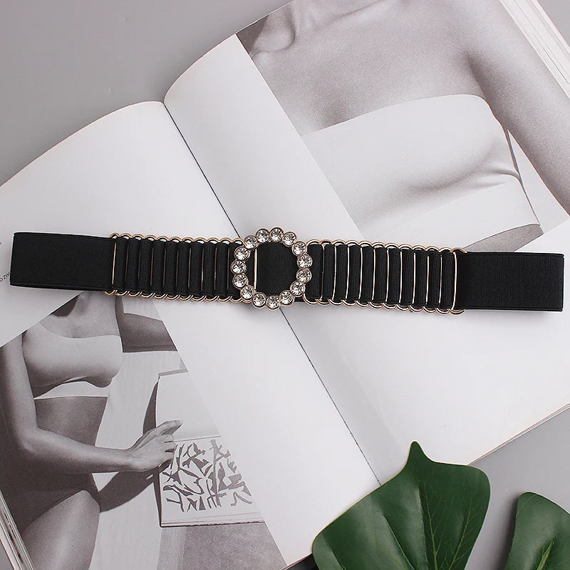 Black elastic belt with ornate round rhinestone center buckle on a stretch strap