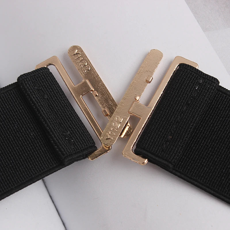 Gold-tone clasp hardware on black elastic belt strap with two interlocking ends