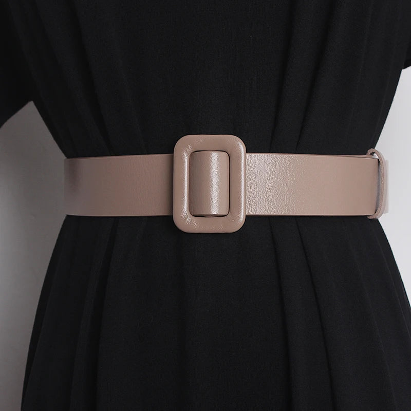 Narrow leather belt on dress waist, light beige with rectangular buckle