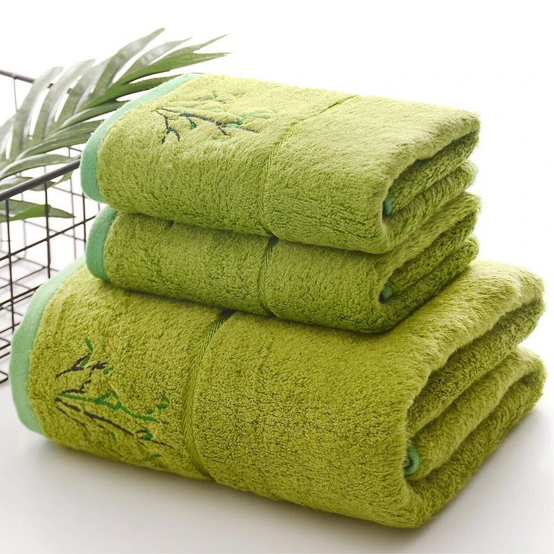 Thick green bath towel stack with embroidered green sprig detail on folded terry