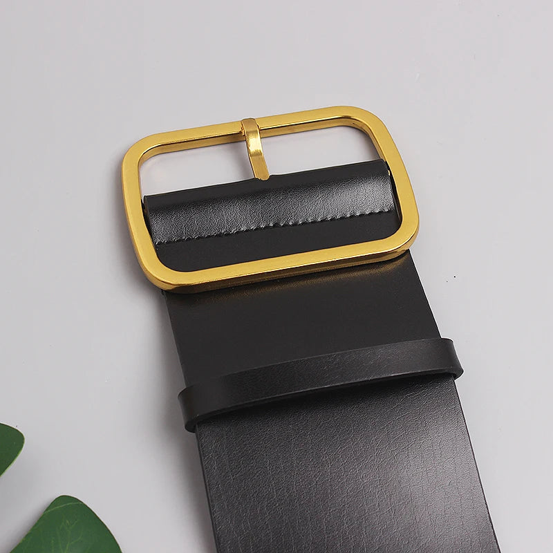 Close-up black leather belt with gold rectangular buckle and grain texture