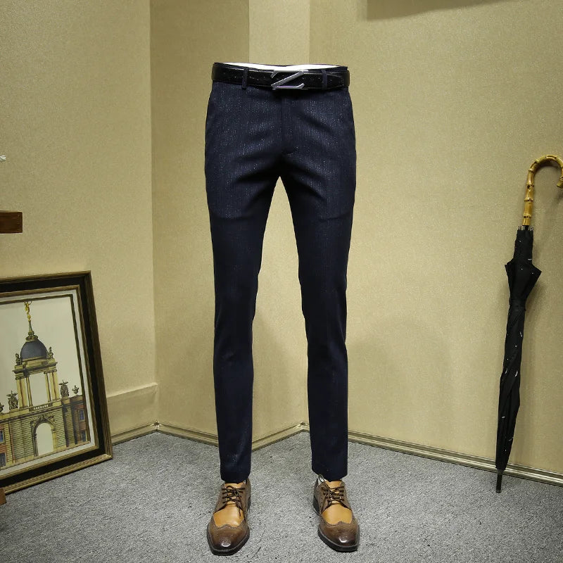 Dark blue pants displayed against a beige wall with a framed picture and umbrella in the background.