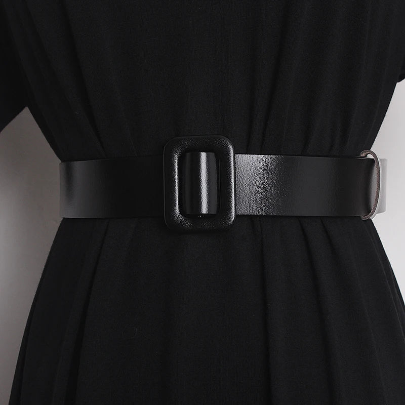 Narrow black leather belt on dress waist with rectangular buckle