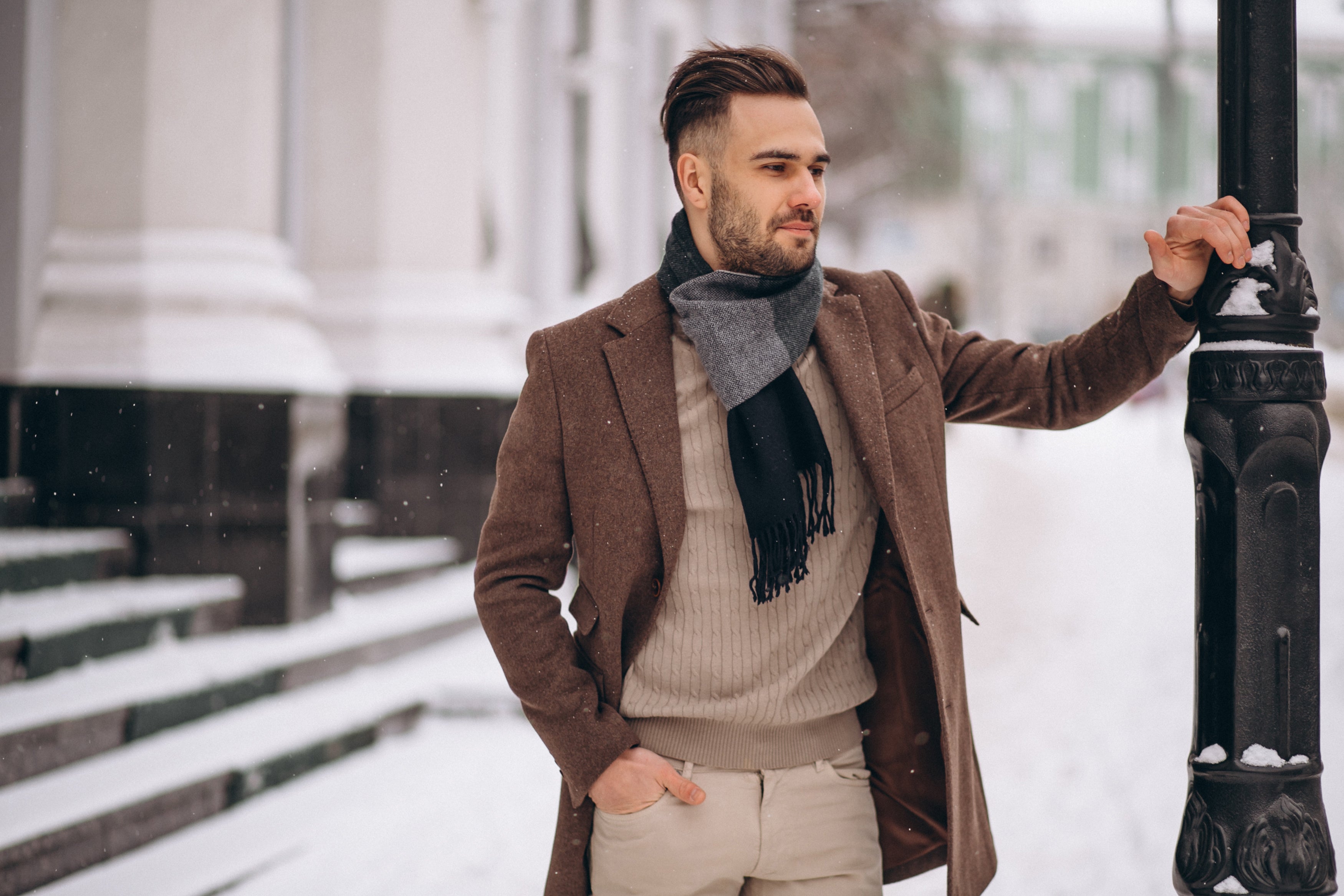 Man in a brown coat and scarf standing outdoors in winter