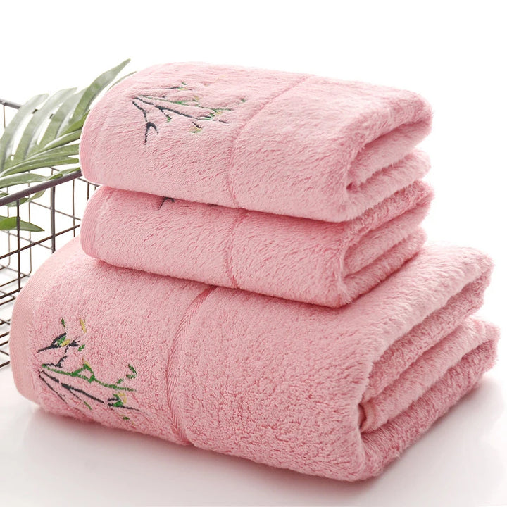 Thick pink towel stack with green embroidered sprig detail on folded terry surface