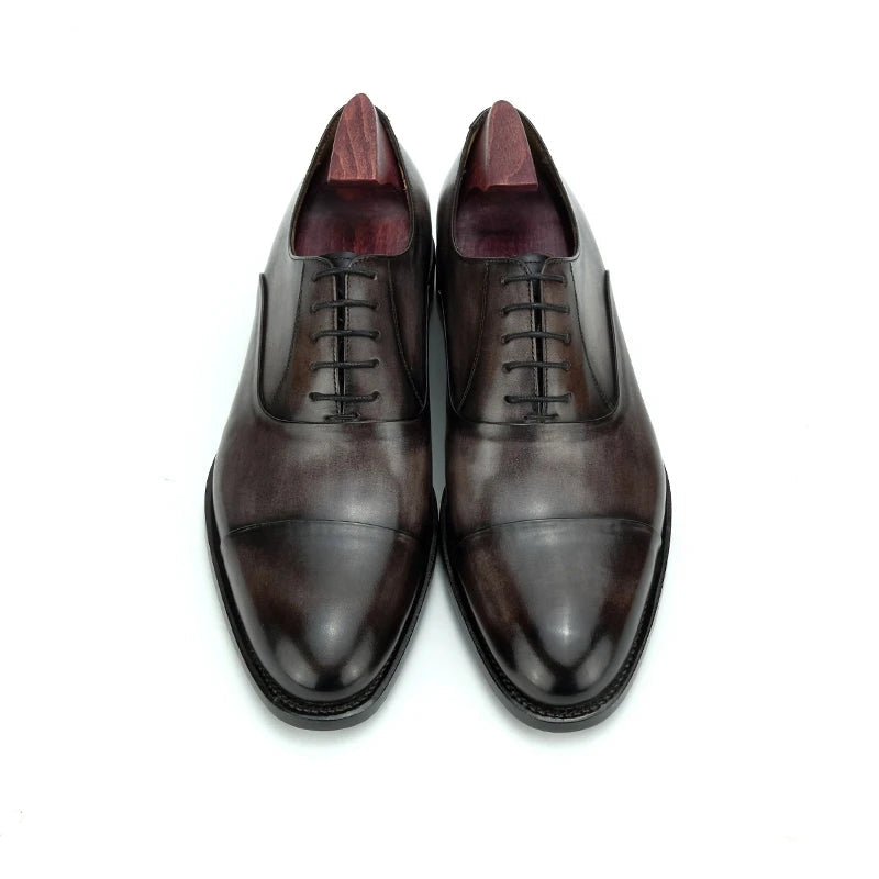 Pair of men's oxford dress shoes, front view, dark patina leather with lace-up vamp