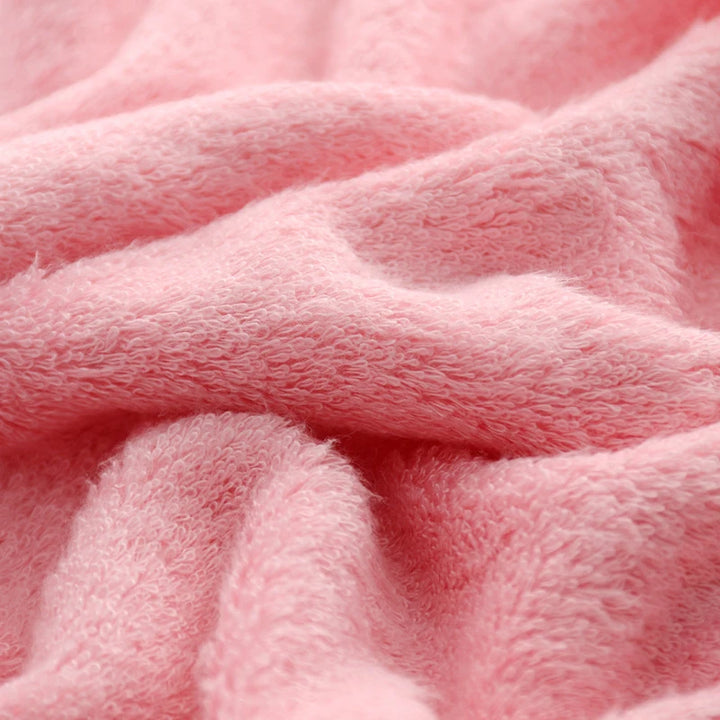 Close-up pink bath towel texture with soft terry loops and visible towel folds