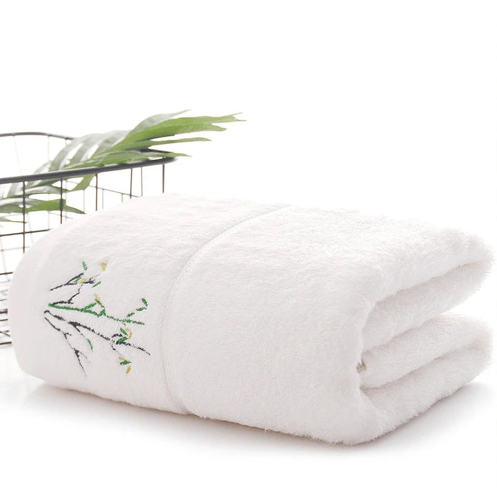 White bamboo-fiber bath towel set, folded with embroidered bamboo leaf