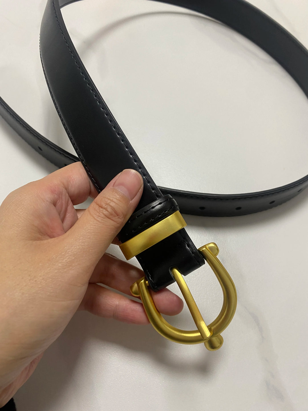 Black leather waist belt with gold-tone buckle ring, punched holes, and adjustable strap
