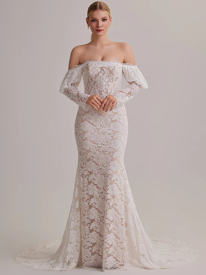 Woman wearing a white lace off-shoulder gown against a plain background