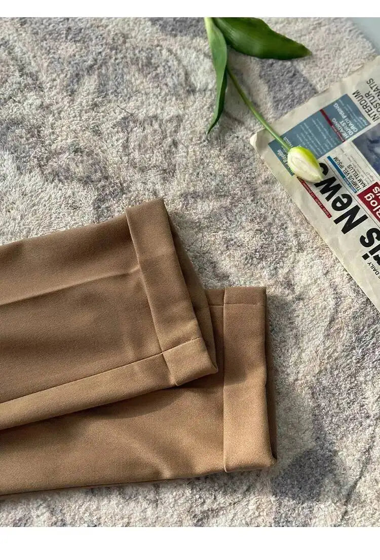 Khaki beige flat-front formal dress pants folded with pleats and belt loops visible.