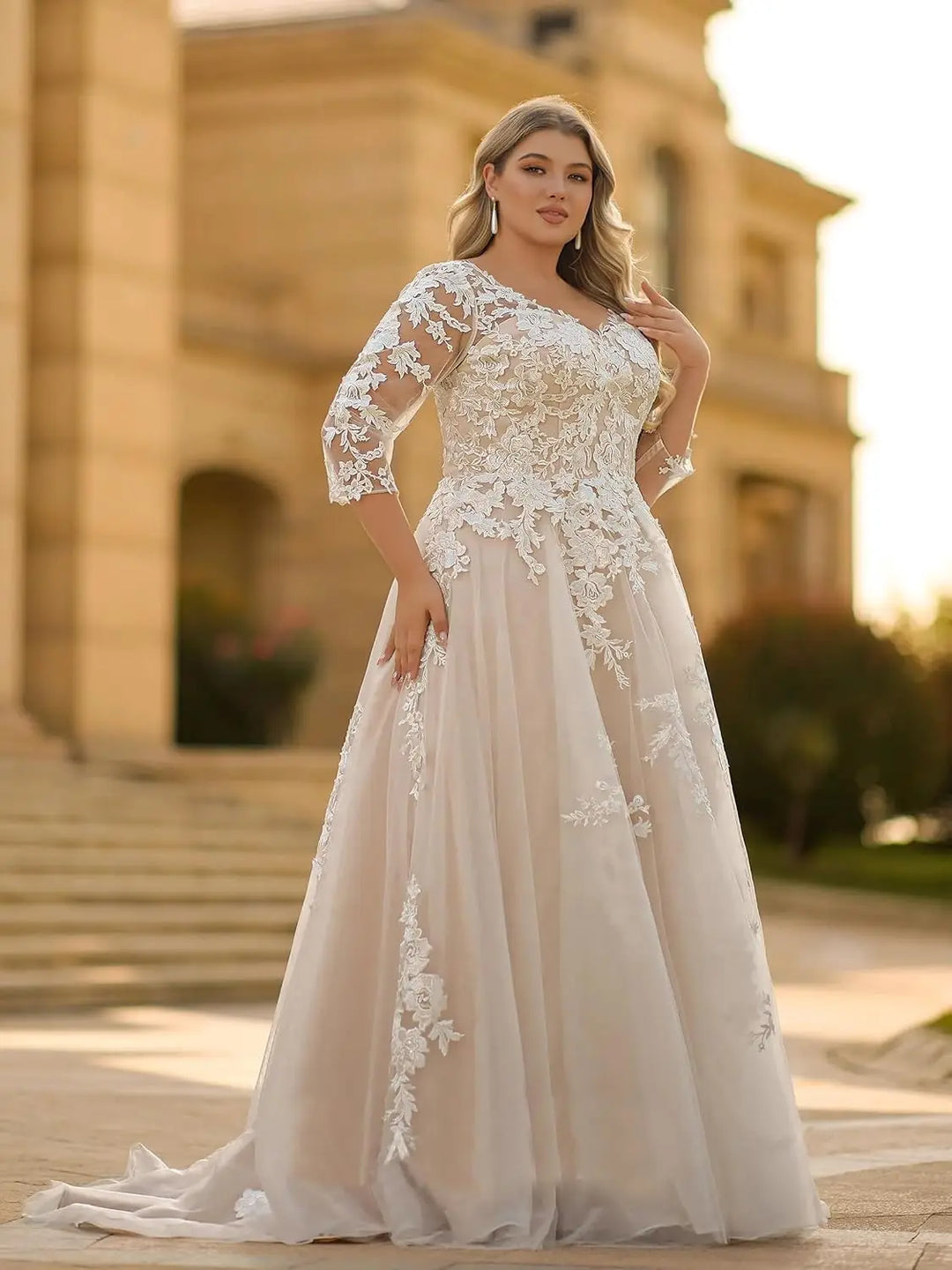 Ivory lace plus-size wedding dress with 3/4 sleeves, fitted bodice, and full tulle skirt.