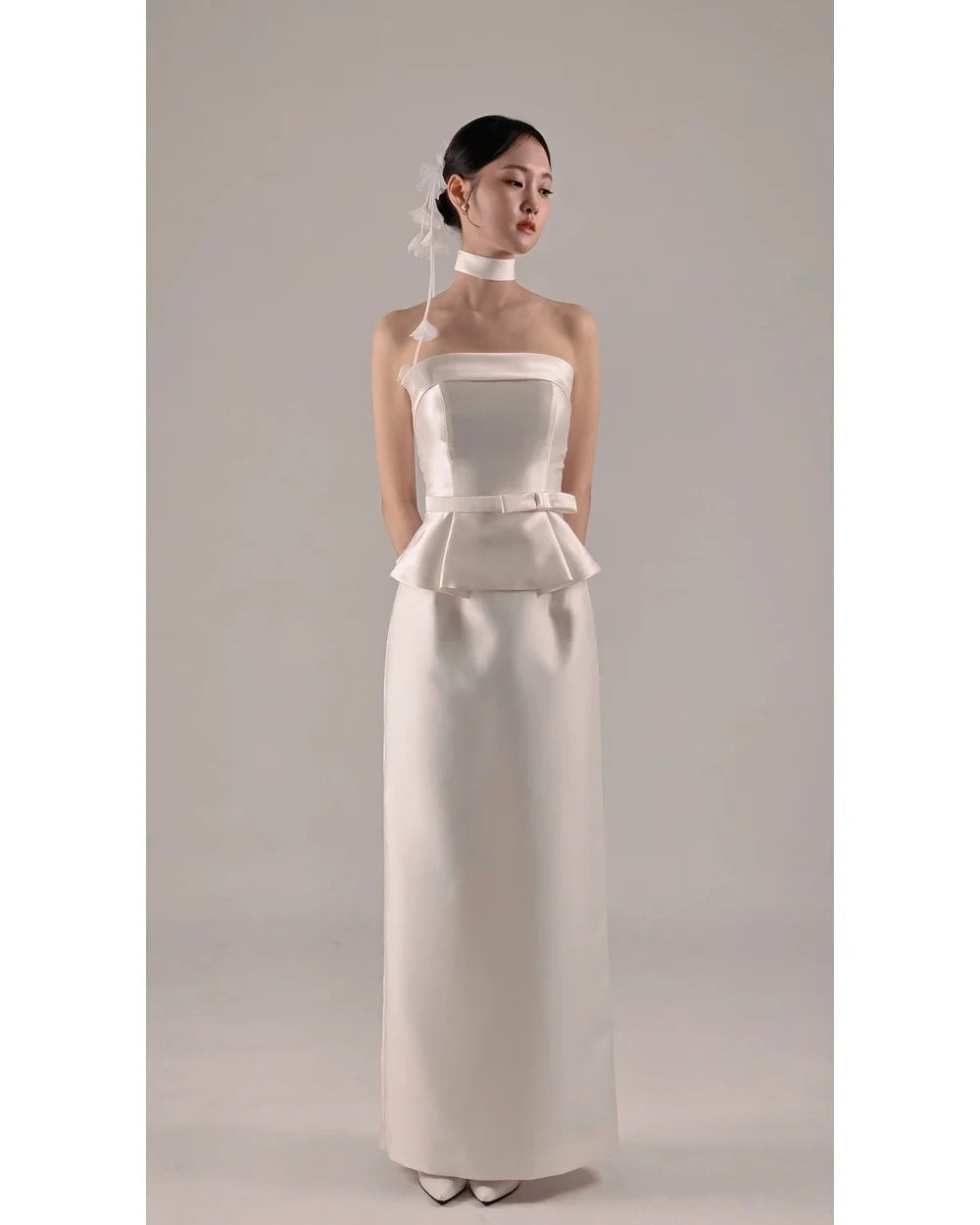 White strapless satin wedding dress with structured bust and layered peplum waist