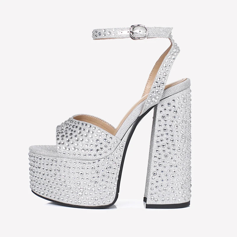 Silver crystal platform sandals with ankle strap and tall block heel, close-up view.