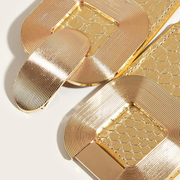 Gold elastic corset belt close-up with textured scale panels and brushed metal buckle.