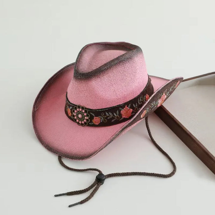 Rose pink cowboy hat with black embroidered band, floral details, and chin ties