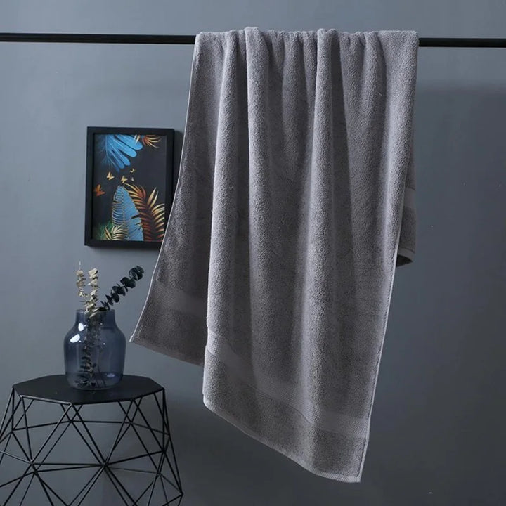 Bath towel in grey, neatly hanging with textured terry surface and straight edge