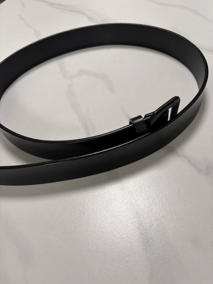 Black leather belt lying flat with rectangular buckle