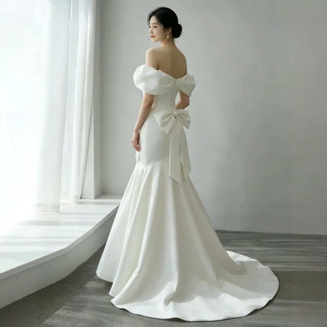 White satin off-shoulder wedding ball gown with soft puff sleeves and tied bow