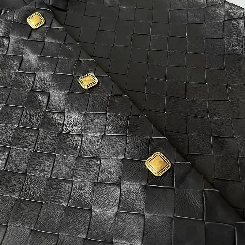 Black vest detail: quilted square panels with gold square buttons at seams