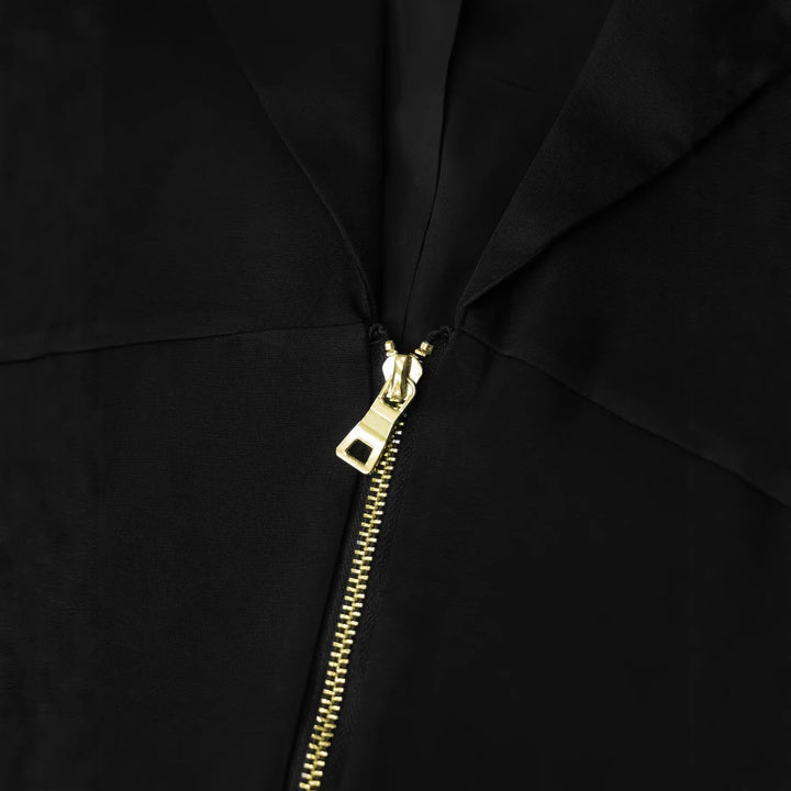 Black blazer neckline detail with gold zipper pull and clasp hardware.