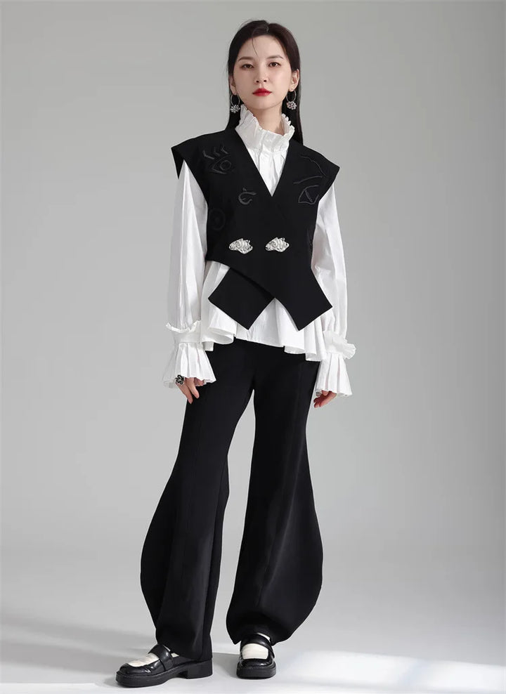 Black irregular women’s suit waistcoat with V-neck and silver buttons over white blouse.