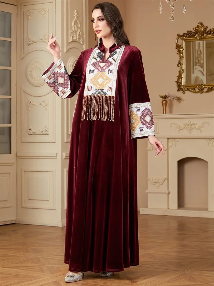 Woman wearing a burgundy dress with intricate patterns in a decorated room.