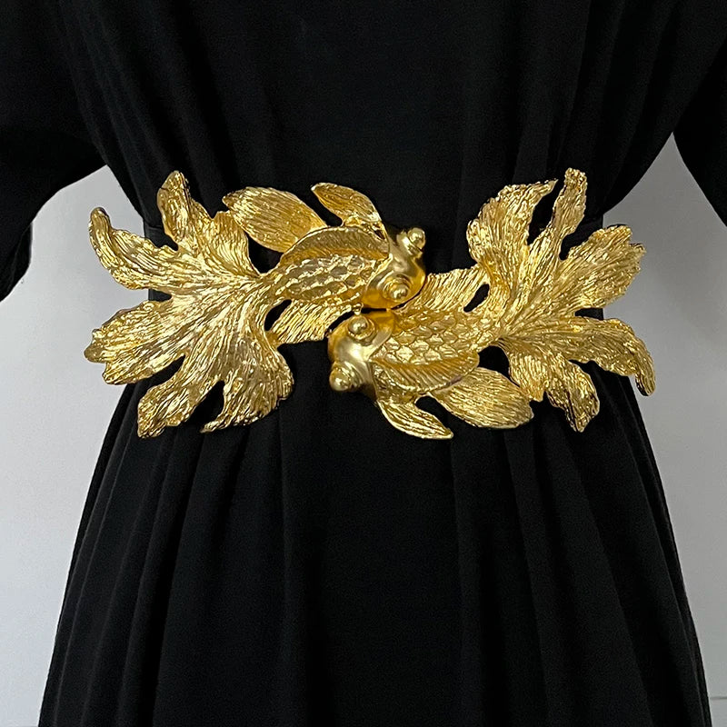 Women’s waist belt featuring a gold fish buckle over black dress fabric