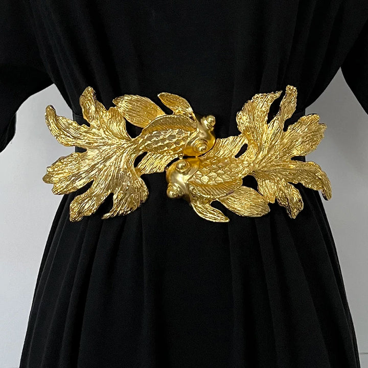 Women’s waist belt featuring a gold fish buckle over black dress fabric