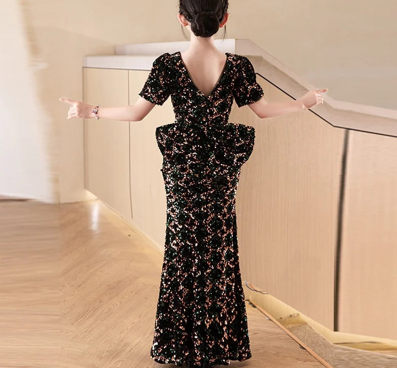 Woman in a black floral dress standing in a modern interior setting with &