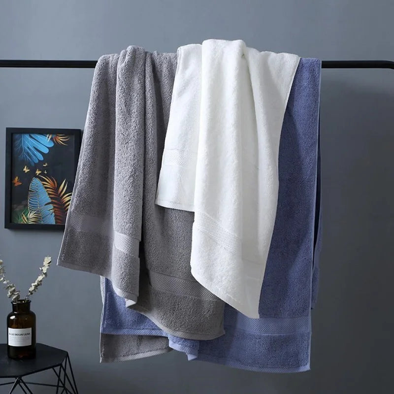 Bath towel set with grey, white, and blue towels, draped and folded over a rack