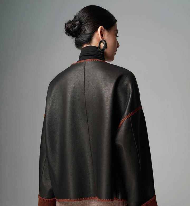 Women’s black goatskin short leather jacket, back view with brown trim and orange stitching