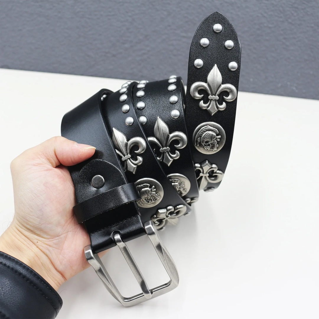 Black leather belt with silver embellishments held by a hand on a white surface.