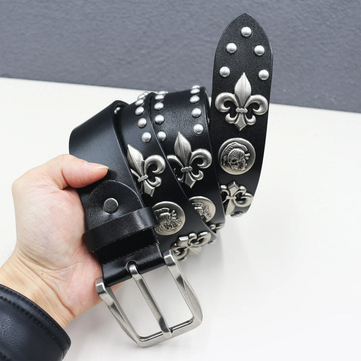 Black leather belt with silver embellishments held by a hand on a white surface.