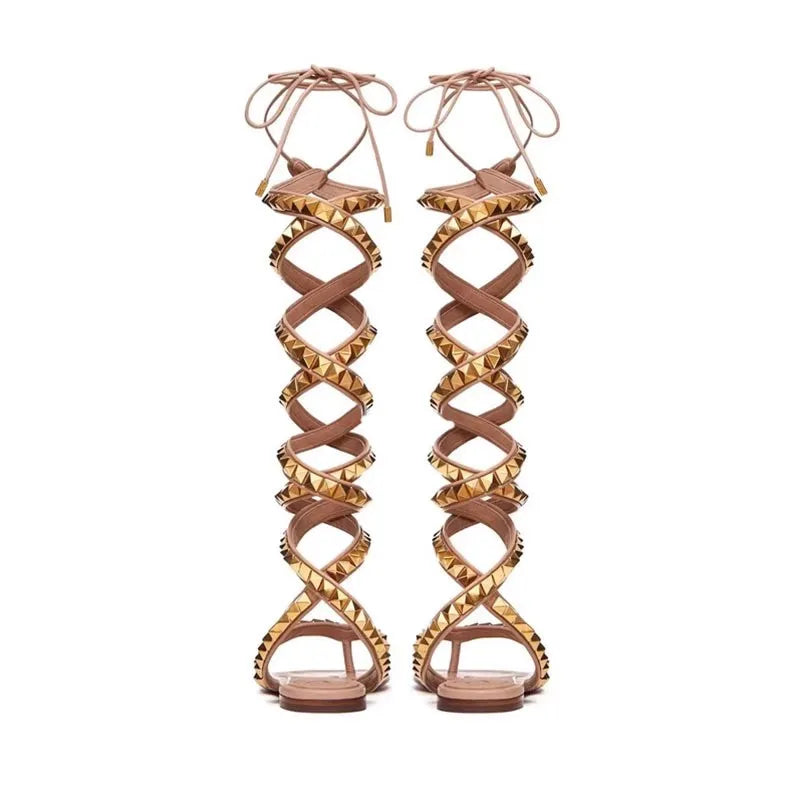 Flat gladiator sandals with crisscross straps, gold studs, and lace-up ankle ties