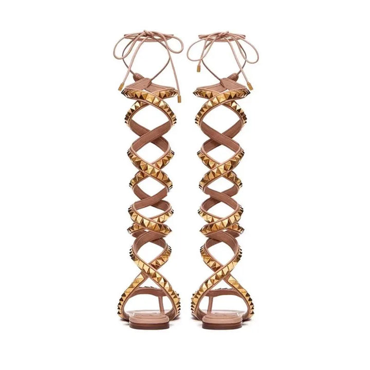 Flat gladiator sandals with crisscross straps, gold studs, and lace-up ankle ties