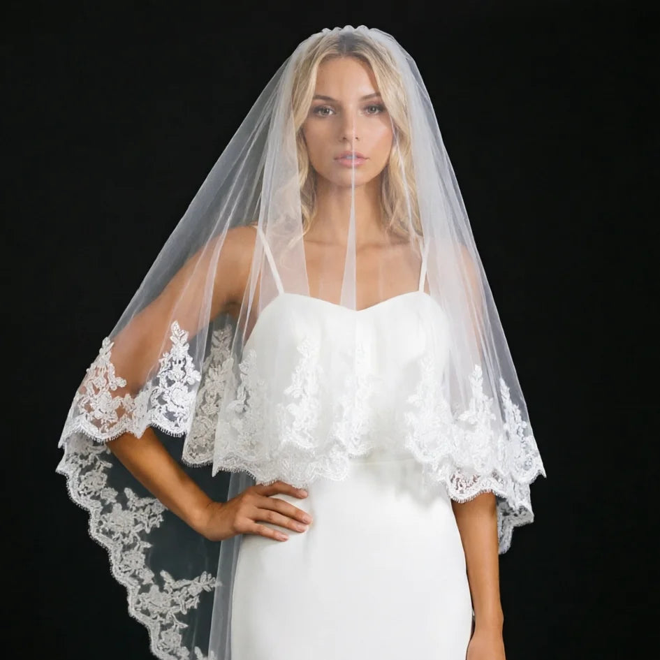 Close view of long white veil with lace sleeves and scalloped hem