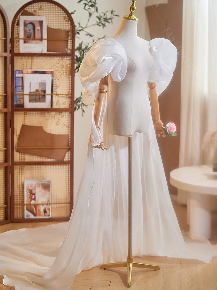 Ivory organza bridal cape on mannequin, long flowing hem and sculpted puff sleeves