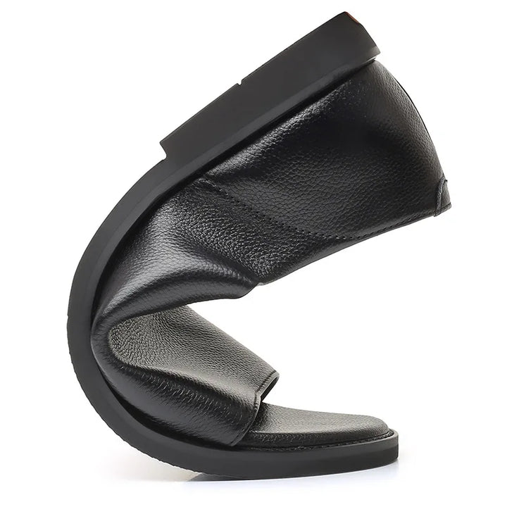 Black leather slide sandal side view, curved toe opening and padded upper