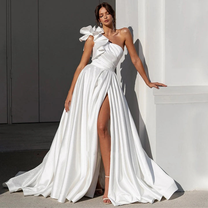 White satin wedding dress with one-shoulder bow and high slit, draped skirt