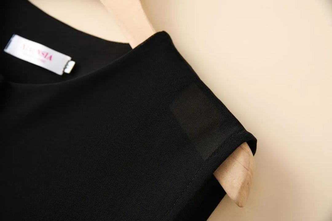 Black mesh vest shoulder detail with round neckline and partial label