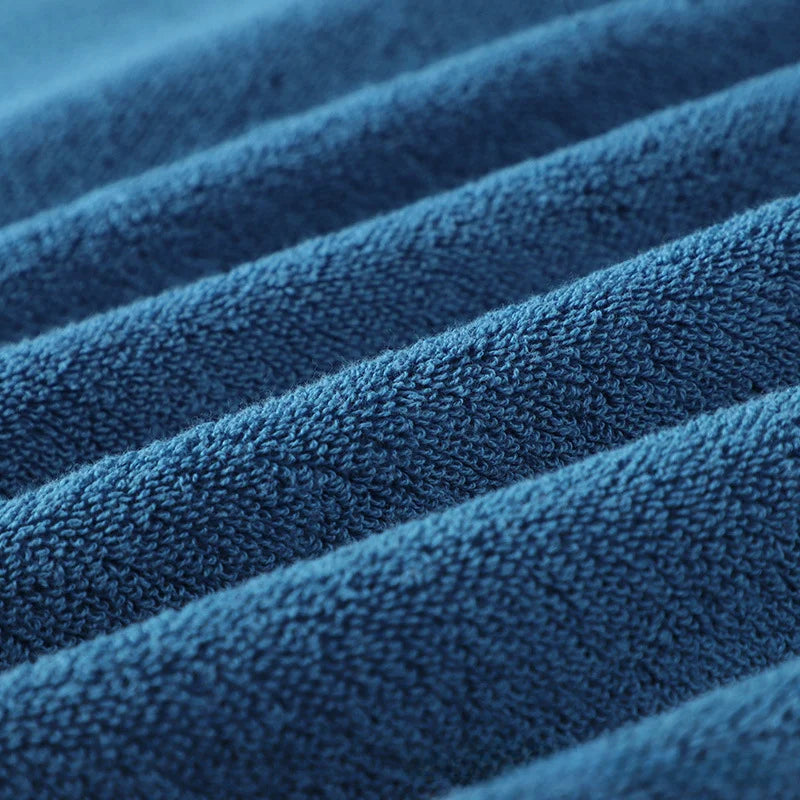 Blue cotton bath towel fabric close-up with soft loop texture and stitched edging