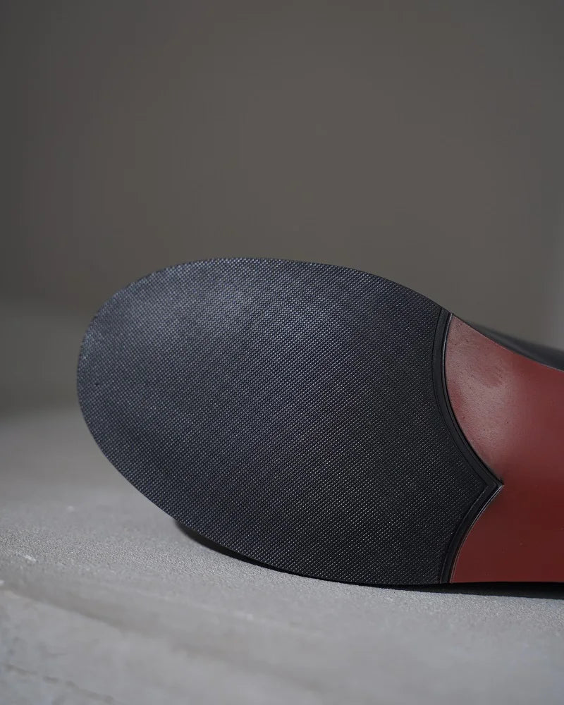 Leather lace-up flat shoe outsole close-up with dark rubber sole and pink lining