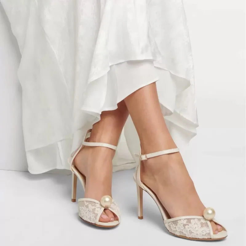 White lace open-toe high heels with ankle strap and pearl button accents