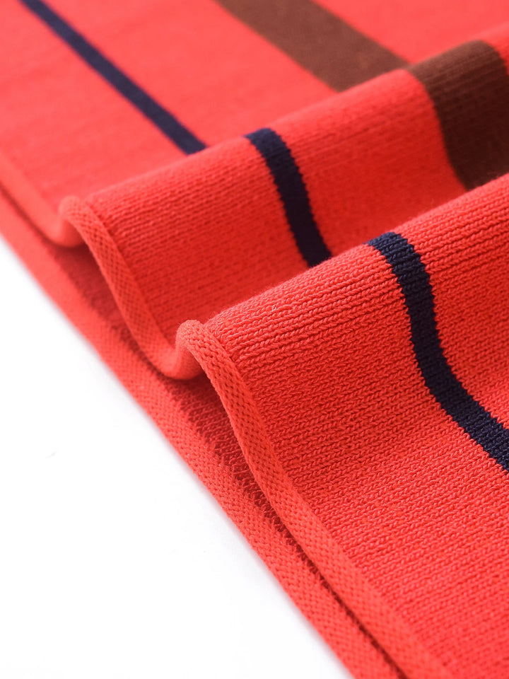 Orange-red knit polo sweater sleeve hem with navy and brown striped ribbing
