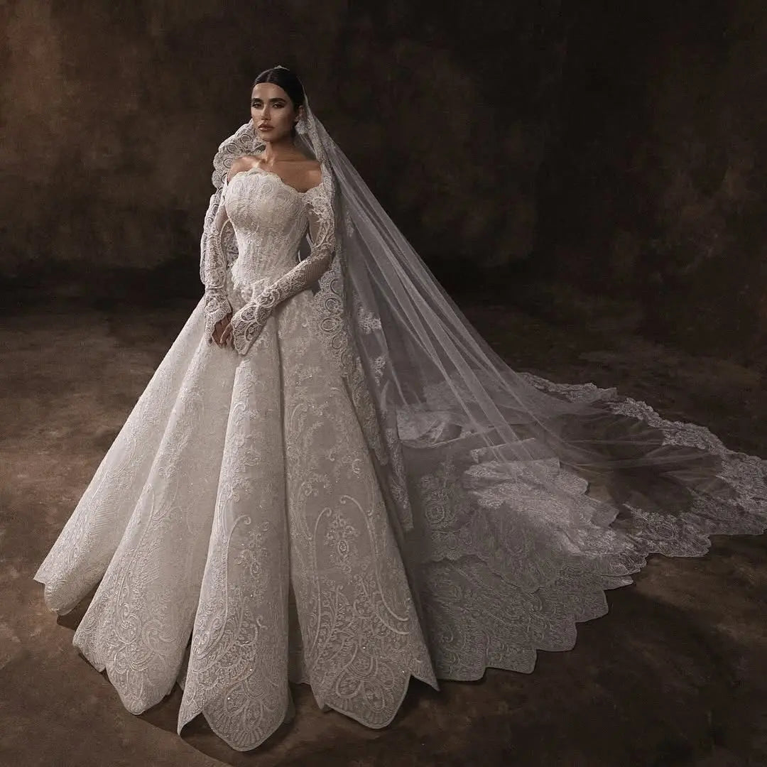 White lace boat-neck bridal gown with long sleeves, full skirt, and flowing veil