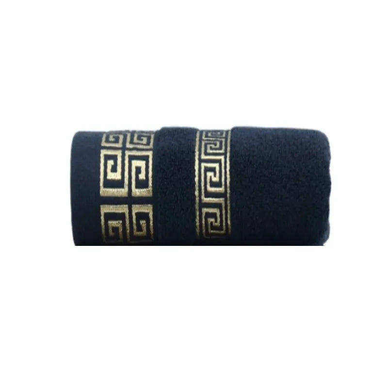 Cotton bathroom towel set in dark blue with gold Greek border, rolled.