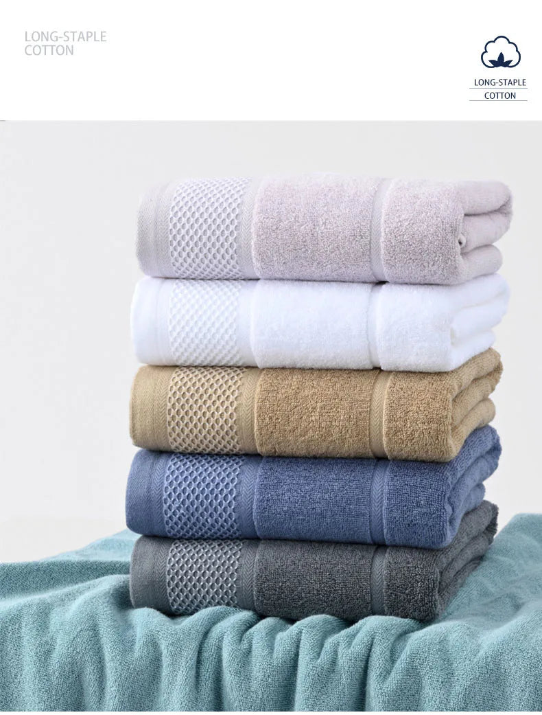 Thick cotton towel set in lavender, white, tan, and blue-gray folded into neat stacks.